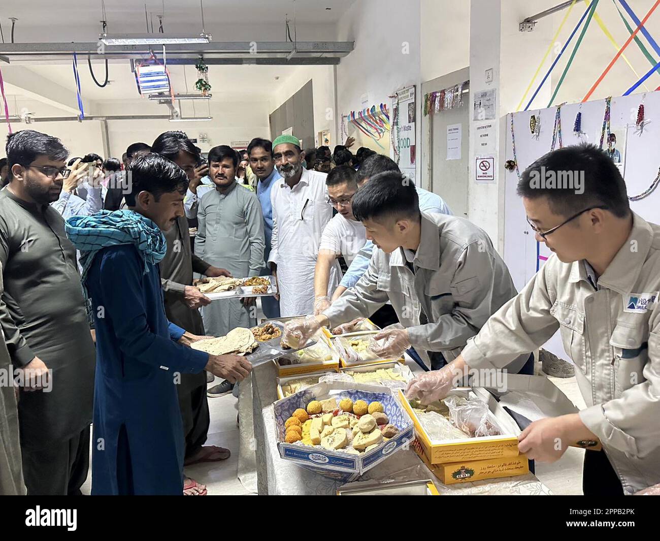 Islamabad. 22nd Apr, 2023. Chinese staff members of the Thar Coal Block-II Coal Electricity Integration project distribute food to Pakistani colleagues to celebrate Eid al-Fitr in the Thar Desert in Pakistan's south Sindh province, April 22, 2023. TO GO WITH "Feature: Chinese staff share joys of Eid festival with Pakistani colleagues at CPEC projects" Credit: Str/Xinhua/Alamy Live News Stock Photo