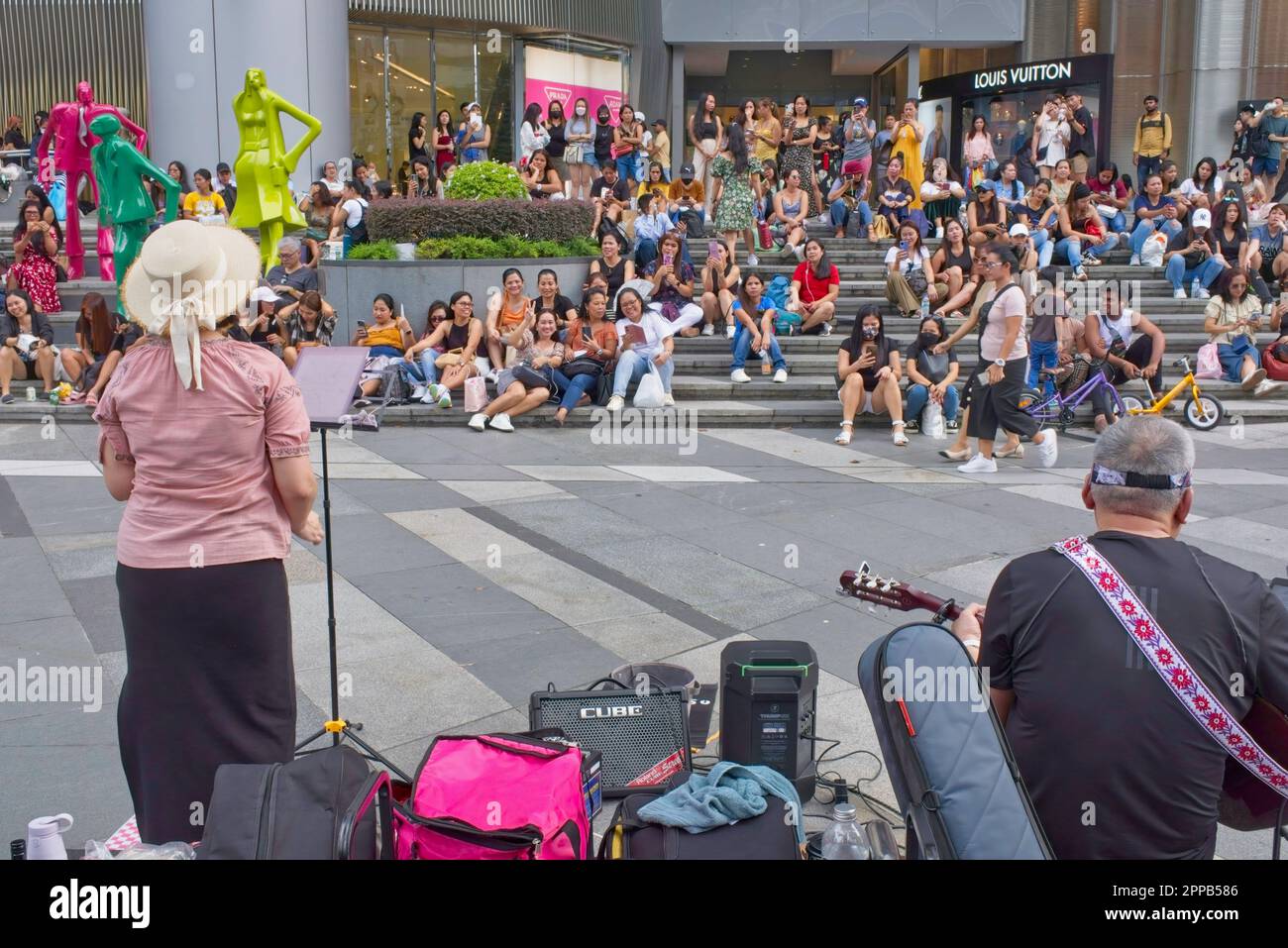 An audience largely consisting of Filipinas working as house maids listening to a two-member band in famous shopping street Orchard Road, Singapore Stock Photo