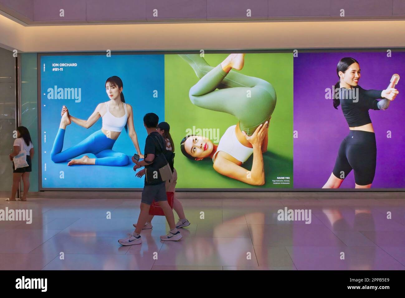 Shoppers at ION Orchard (mall) in Orchard Rd, Singapore pass in front of  large yoga-themed advertisements for co. 'lululemon' selling athletic  apparel Stock Photo - Alamy
