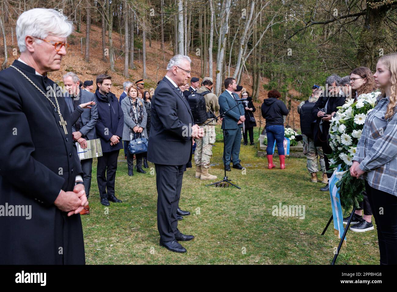 23 April 2023, Bavaria, Flossenbürg: Joachim Herrmann (M, CSU), Minister of the Interior of Bavaria, stands by a wreath in the so-called 'Valley of Death' in memory of the victims of the concentration camp during the commemoration of the 78th anniversary of the liberation of the Flossenbürg concentration camp. On the left is Heinrich Bedford-Strohm, regional bishop of the Evangelical Lutheran Church in Bavaria. Flossenbürg concentration camp had been liberated by the U.S. Army on April 23, 1945. Of about 100,000 people imprisoned there or in the subcamps, about 30,000 had died. Photo: Daniel K Stock Photo