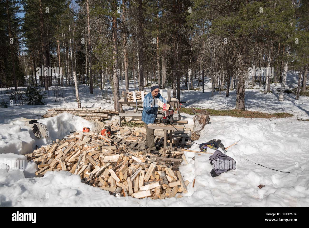 Elderly woman splits wood with a hydraulic wood splitter Stock Photo