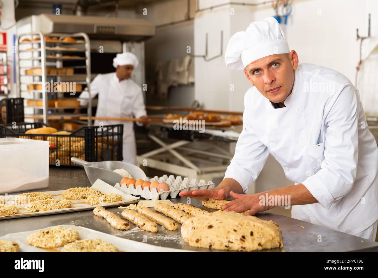 male baker in white uniform rolling out dough in kitchen Stock Photo ...