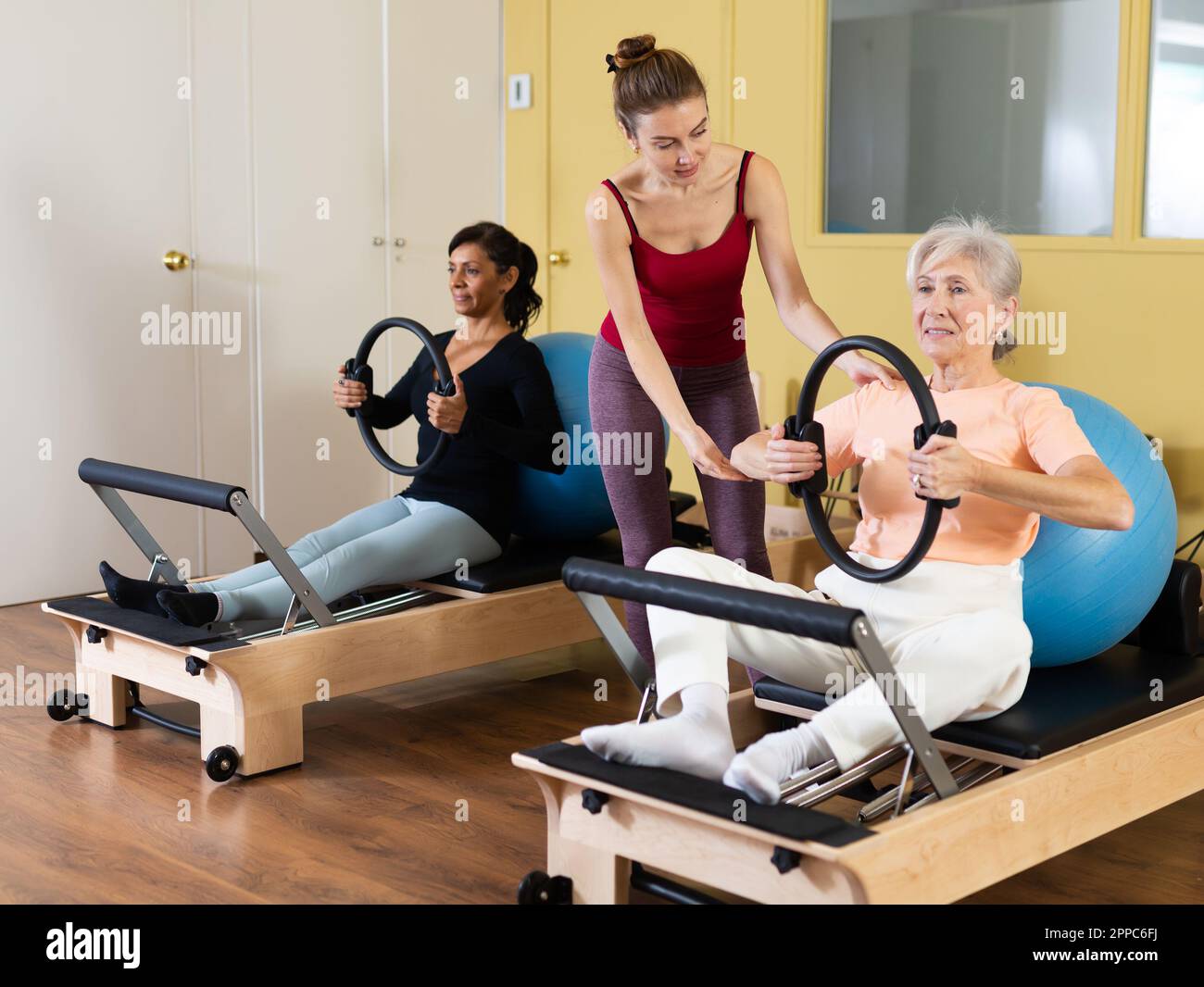 Two women perform an exercise using special rings and a fitball Stock ...