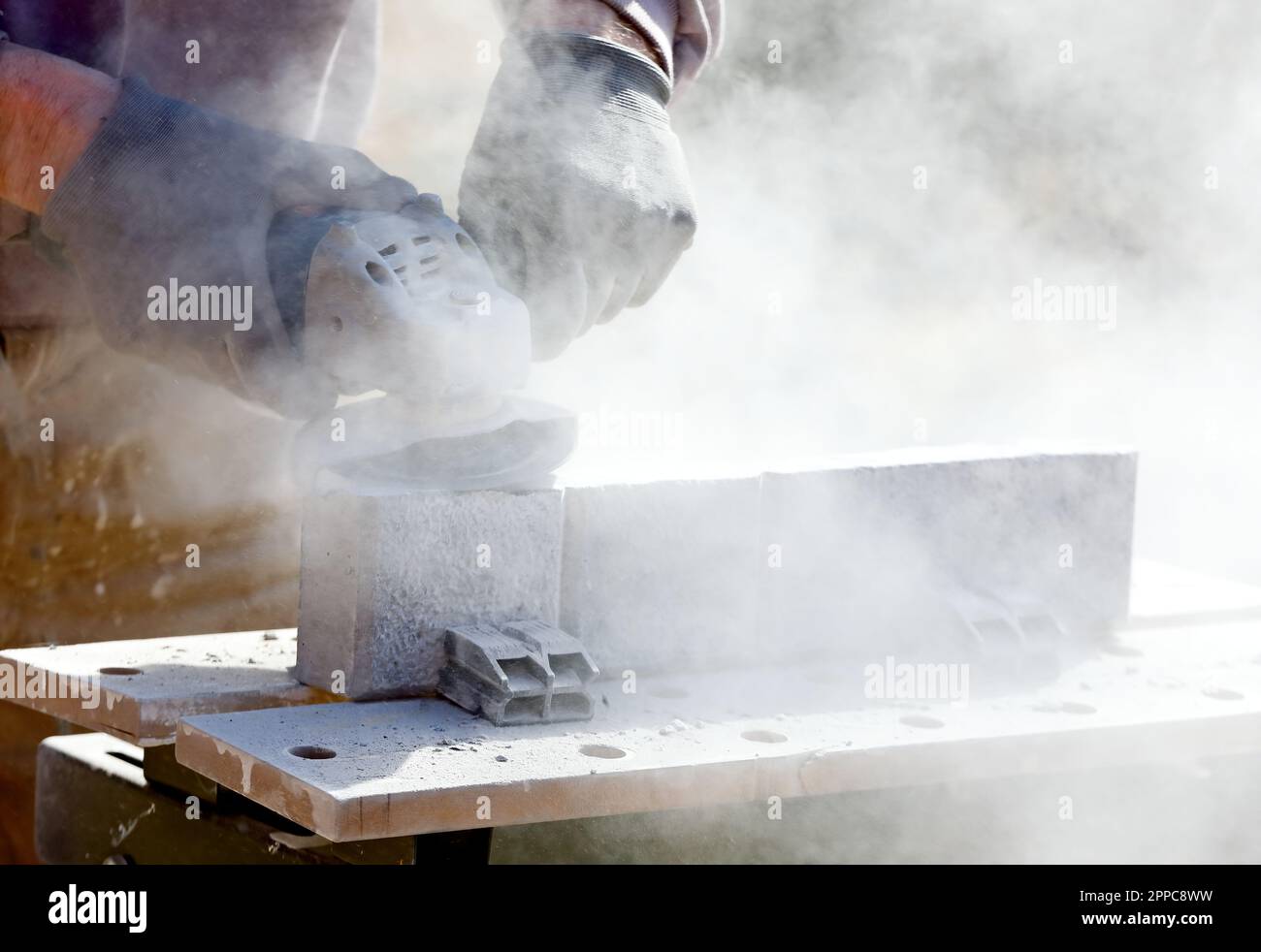 A man cutting concrete balk with a lot of dust in the air Stock Photo