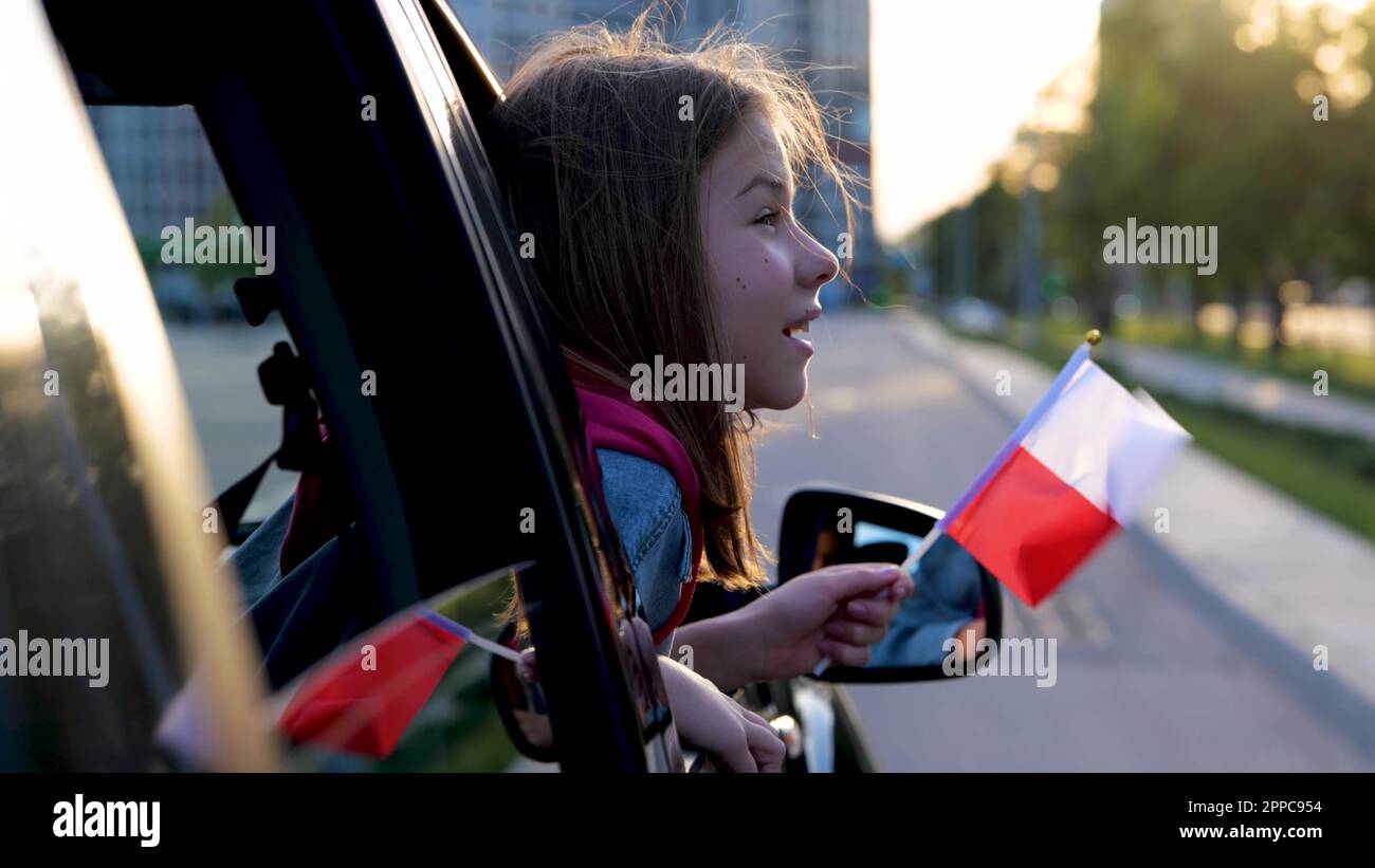 Pretty little girl with small flag of Poland sits in front seat in