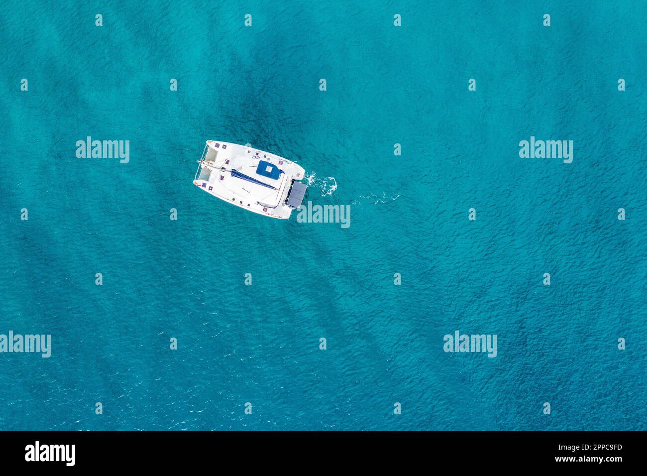 Aerial view of anchored sailing yacht in emerald sea. Aerial view of a