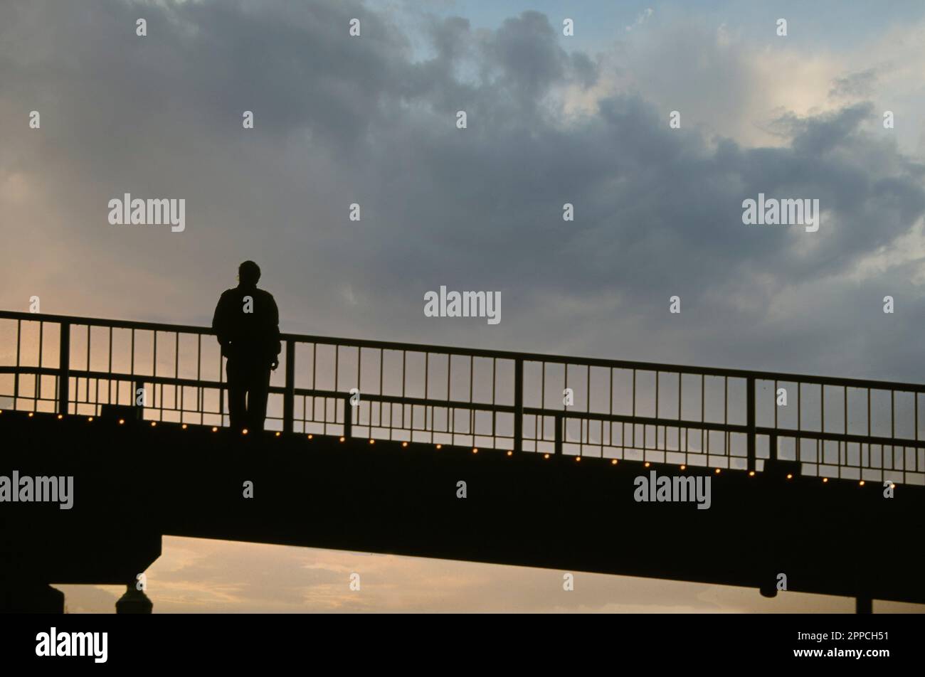 Silhouette of a lonely man  standing on bridge at sunset Stock Photo