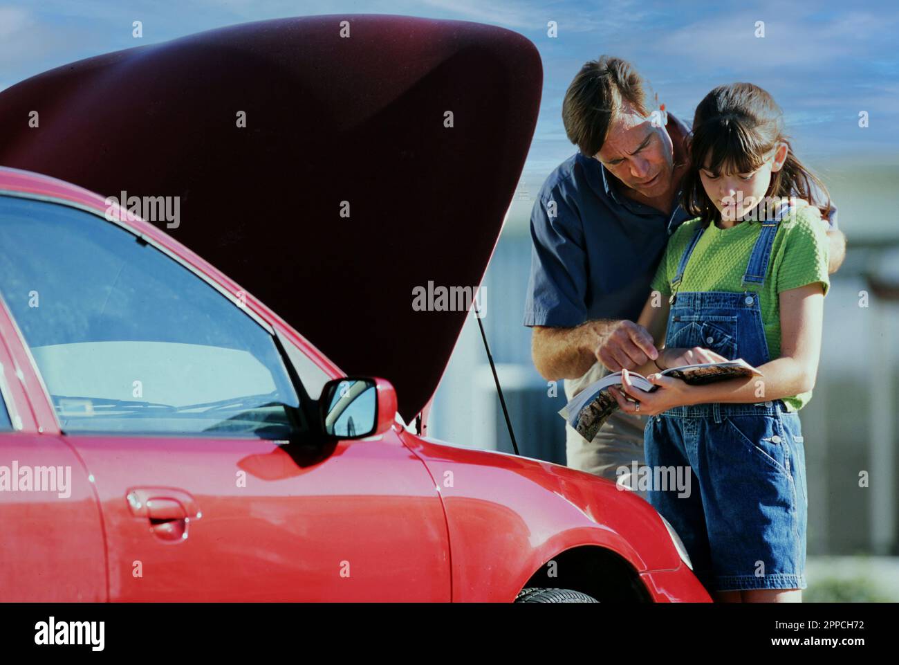 Father teaching teen daughter the mechanics of her new car Stock Photo