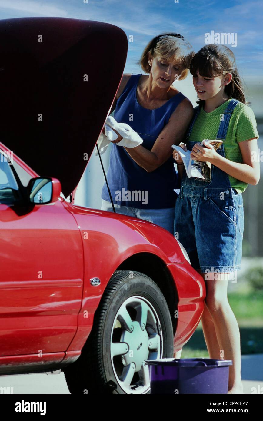 Mother and young teen daughter Learning about car maintenance Stock Photo