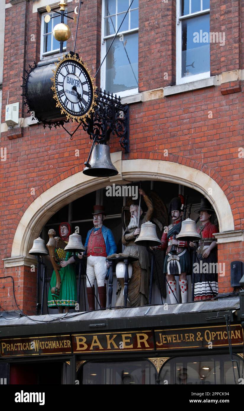 Mechanical chiming clock above Bakers, Edwardian shopfront. Jewellers, watchmakers, opticians, shop in Gloucester, UK. Carillon. Stock Photo