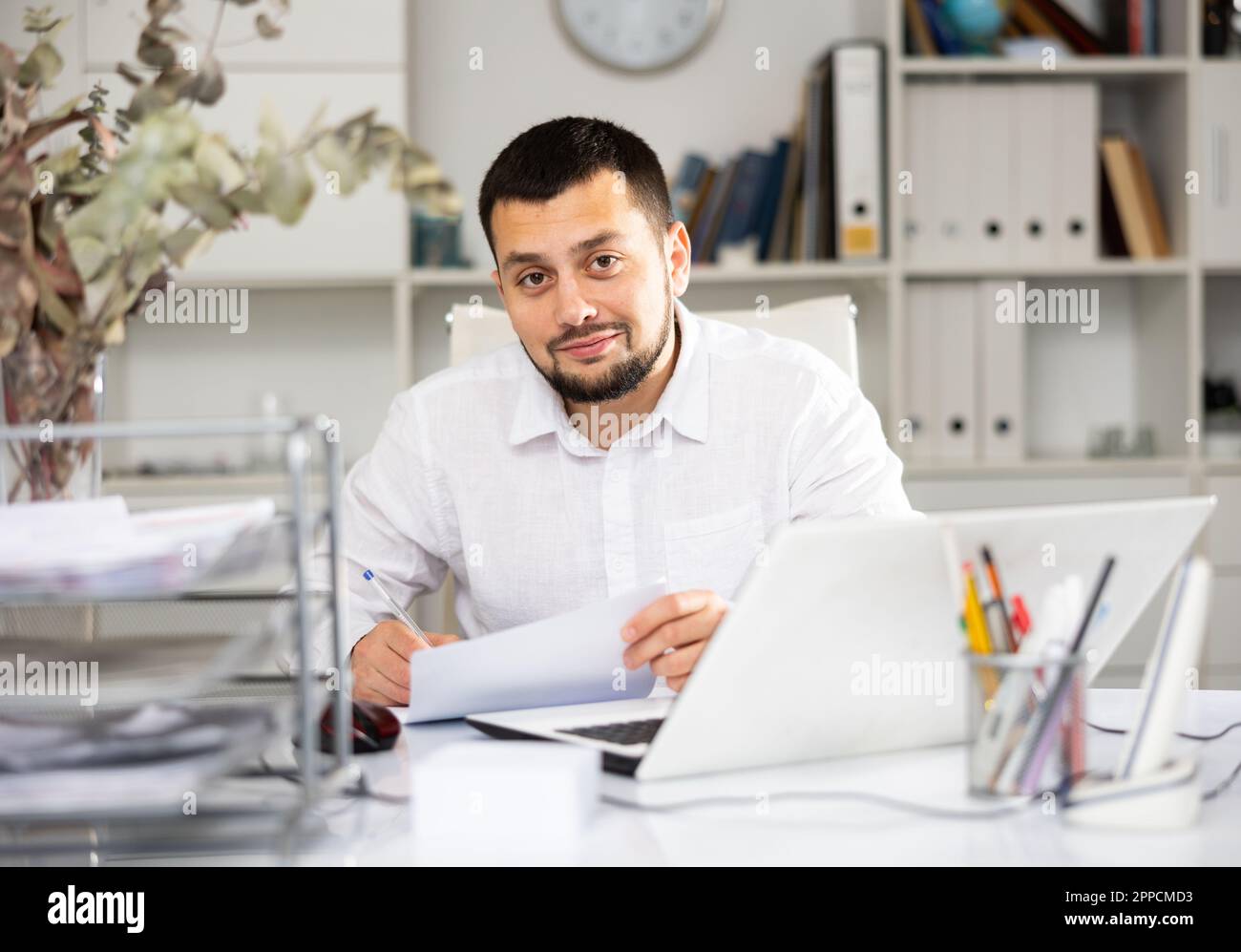 Positive man bookkeeper doing paperwork in office Stock Photo