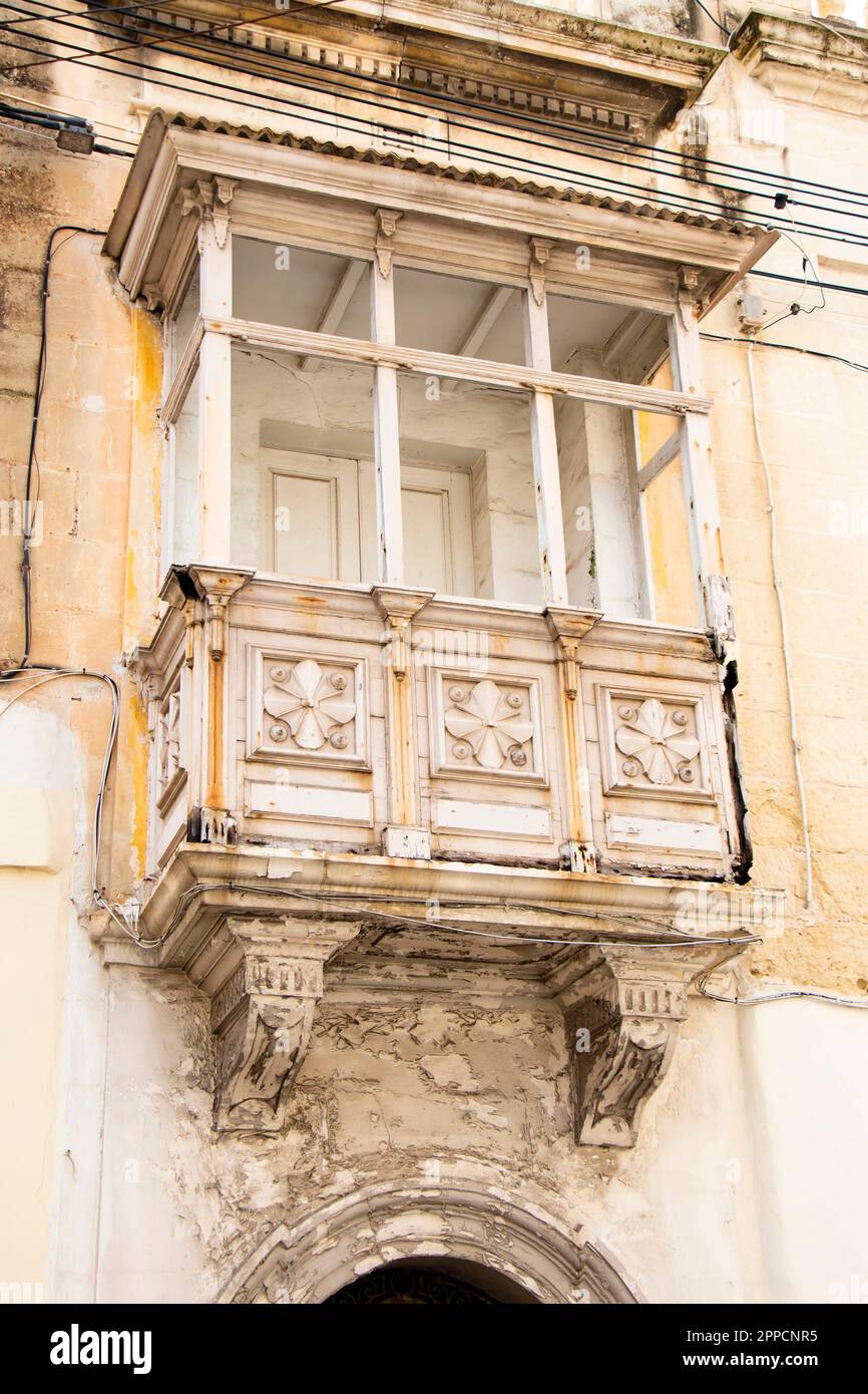 Rabat, Malta - November 13, 2022: Weathered white typical maltese ornate closed wooden balcony, close up Stock Photo