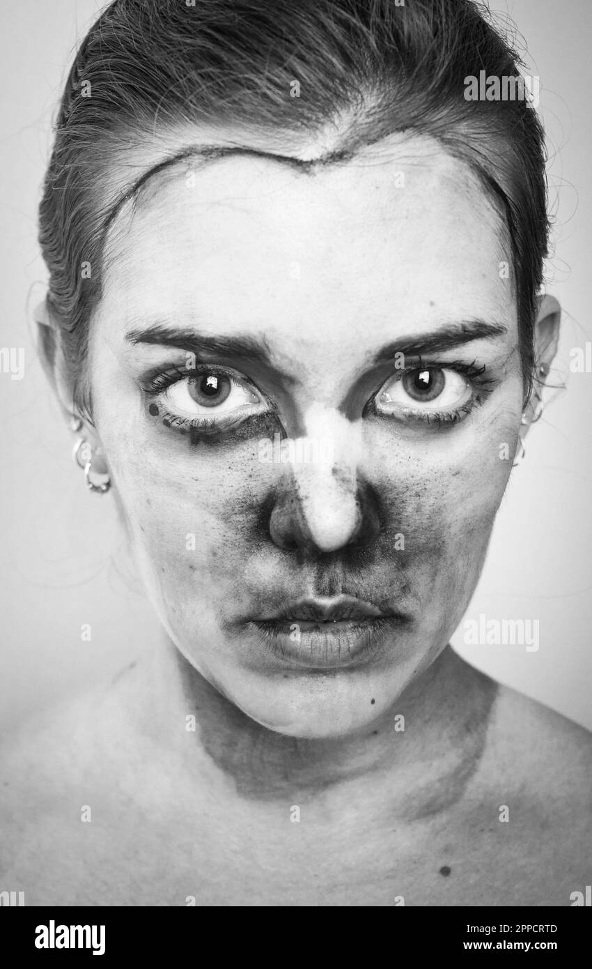 Intense black and white portrait of woman with face paint messily removed, for an emotional stare into the camera. Stock Photo
