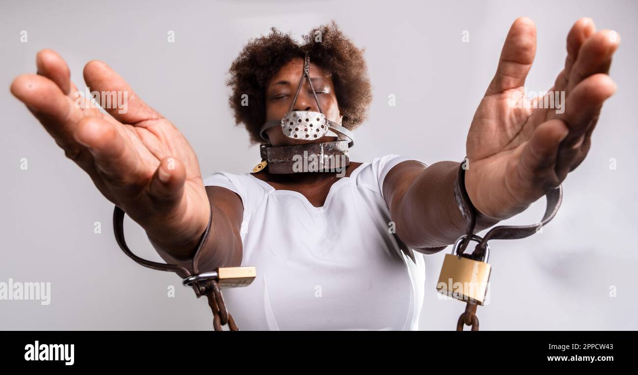 Portrait of sad woman bound with old rusty chains and padlocks, showing hands. Slave trade prevention concept. Stock Photo