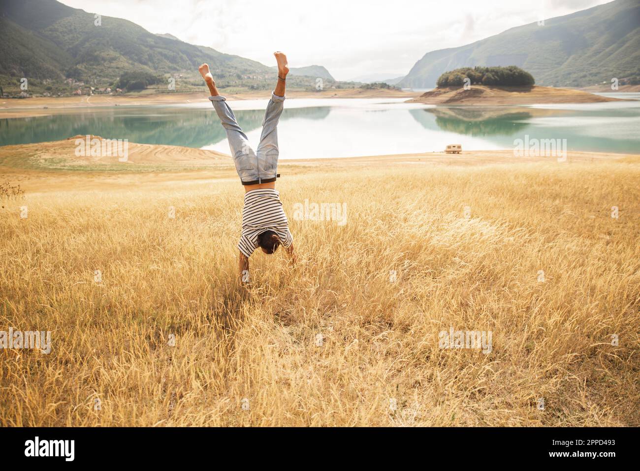 Man doing handstand on dry grass Stock Photo