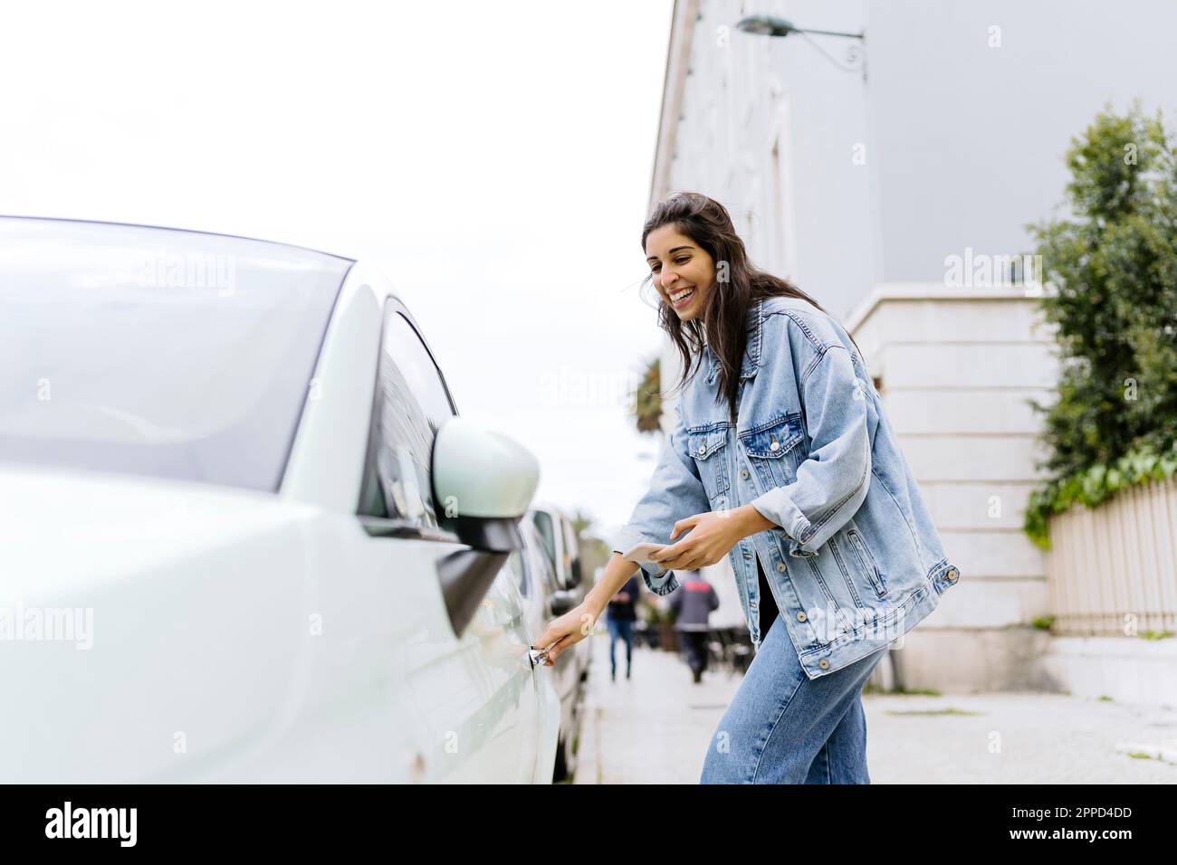 Happy young woman opening car door Stock Photo - Alamy