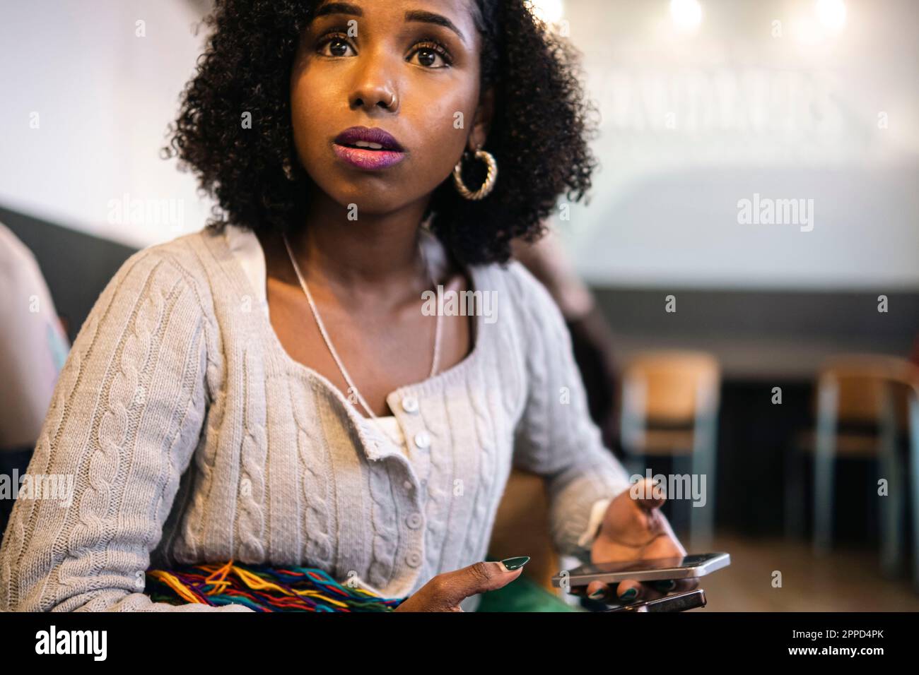 Worried woman with curly hair holding smart phone Stock Photo