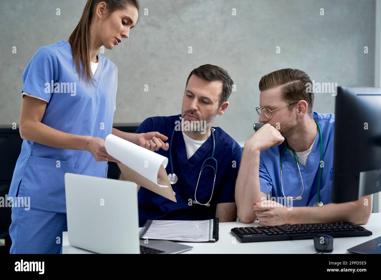 Female doctor discussing over documents with colleagues Stock Photo