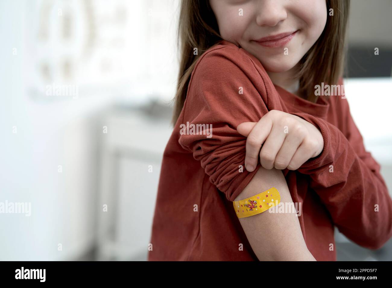 Smiling girl showing adhesive bandage after vaccination in clinic Stock Photo