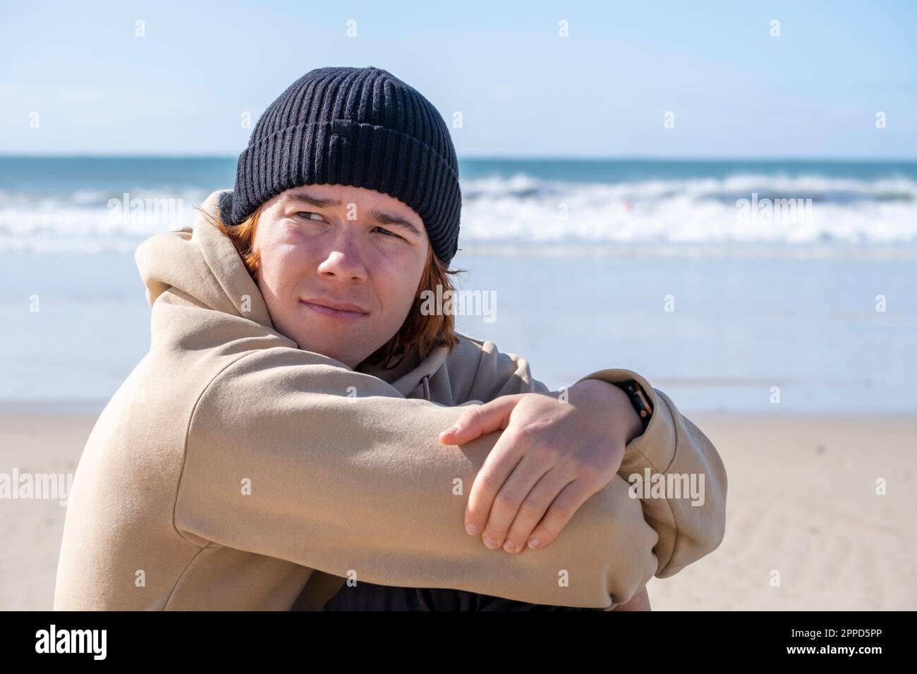 Man hugging knees sitting at beach Stock Photo - Alamy