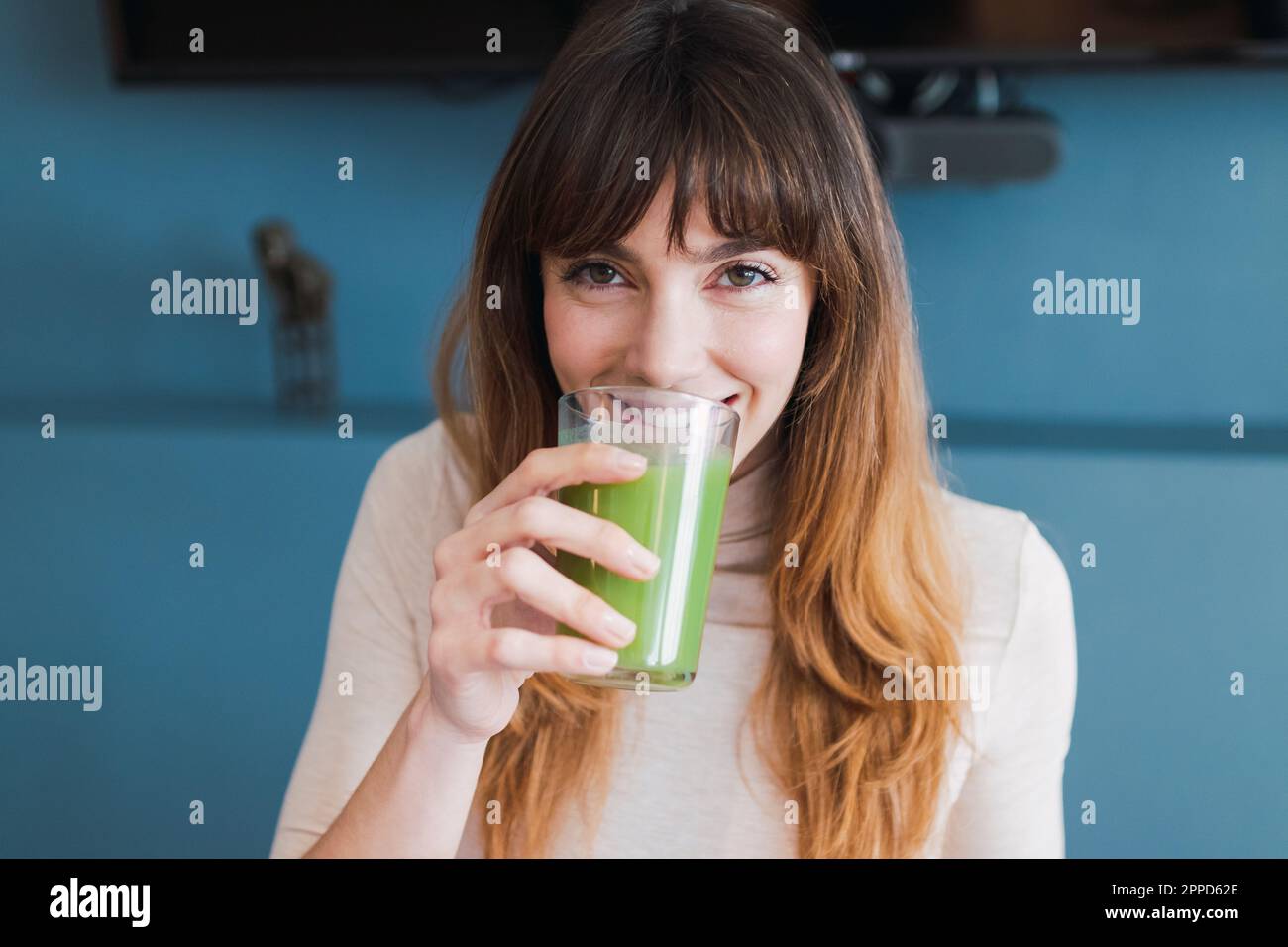 Smiling woman drinking detox juice at home Stock Photo
