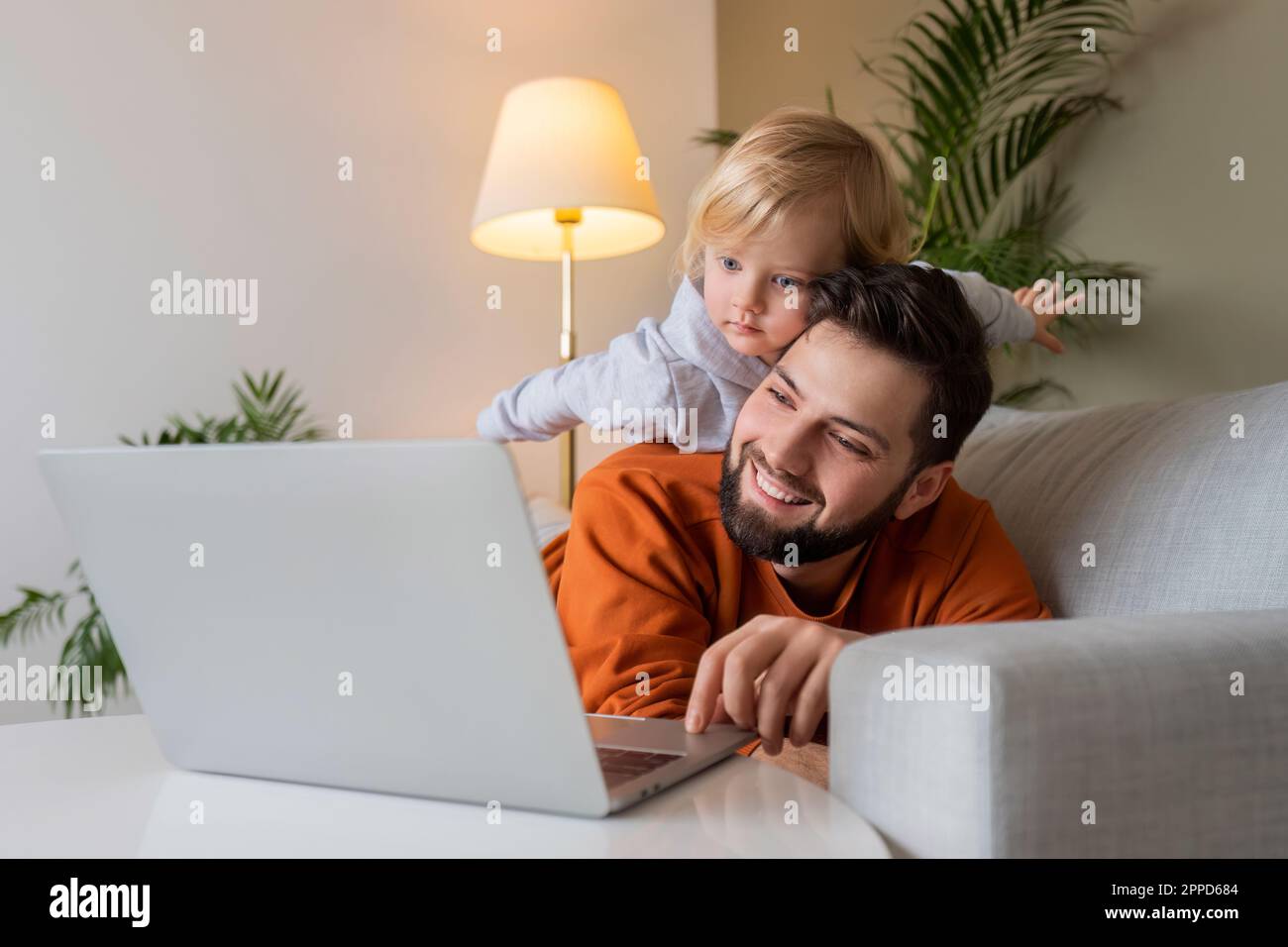 Happy father using laptop with son lying on father at home Stock Photo ...