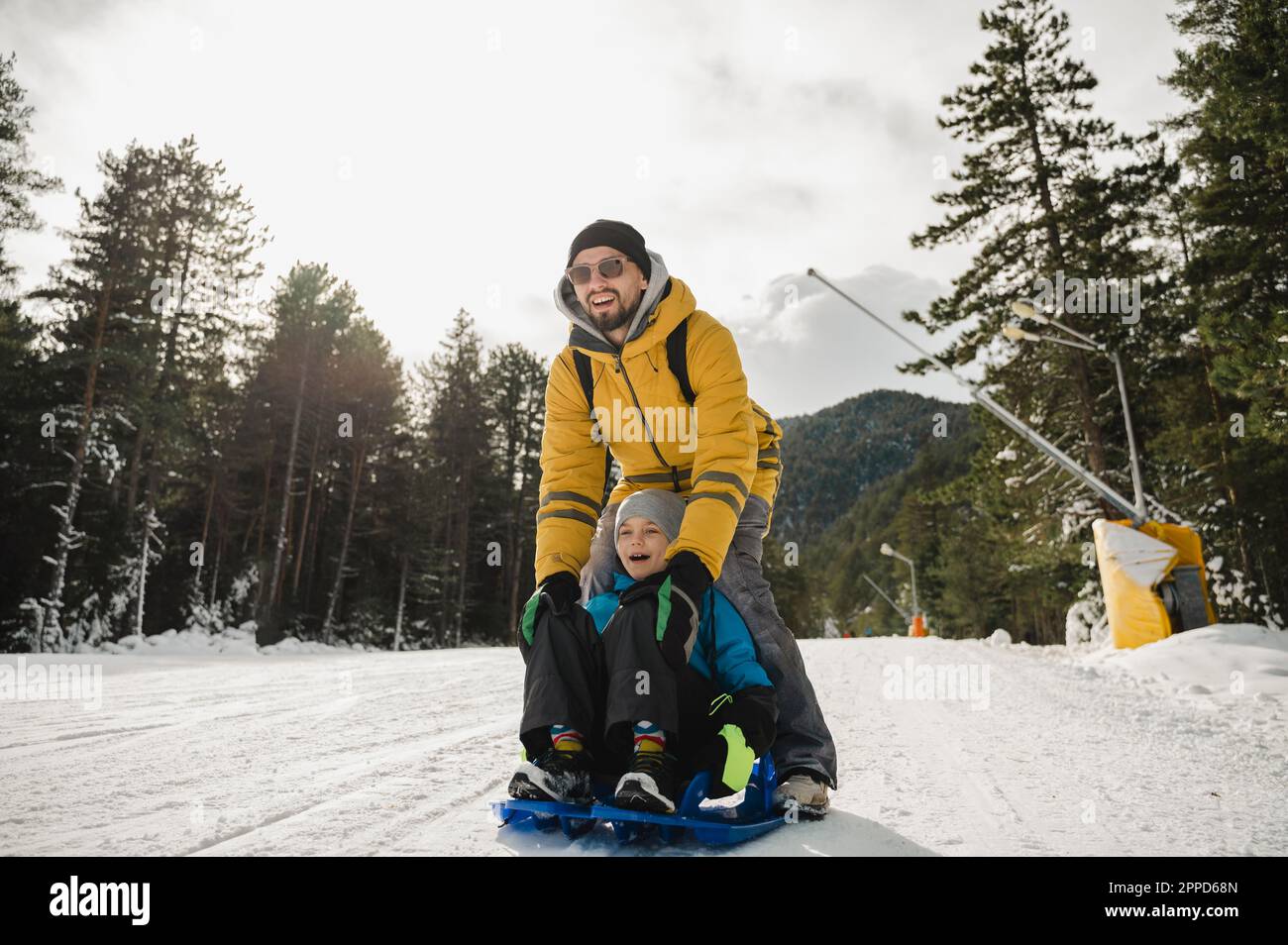 Happy father and son enjoys tobogganing on snow Stock Photo