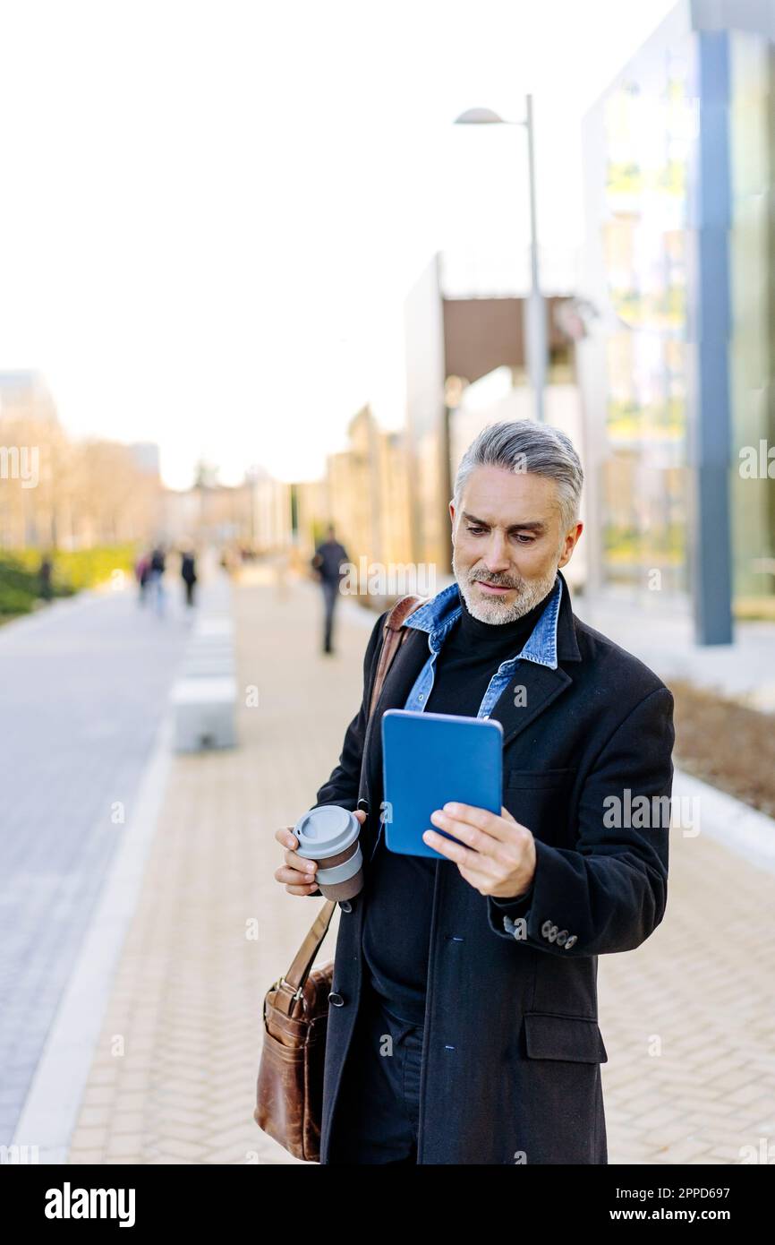 Businessman using tablet PC standing at footpath Stock Photo