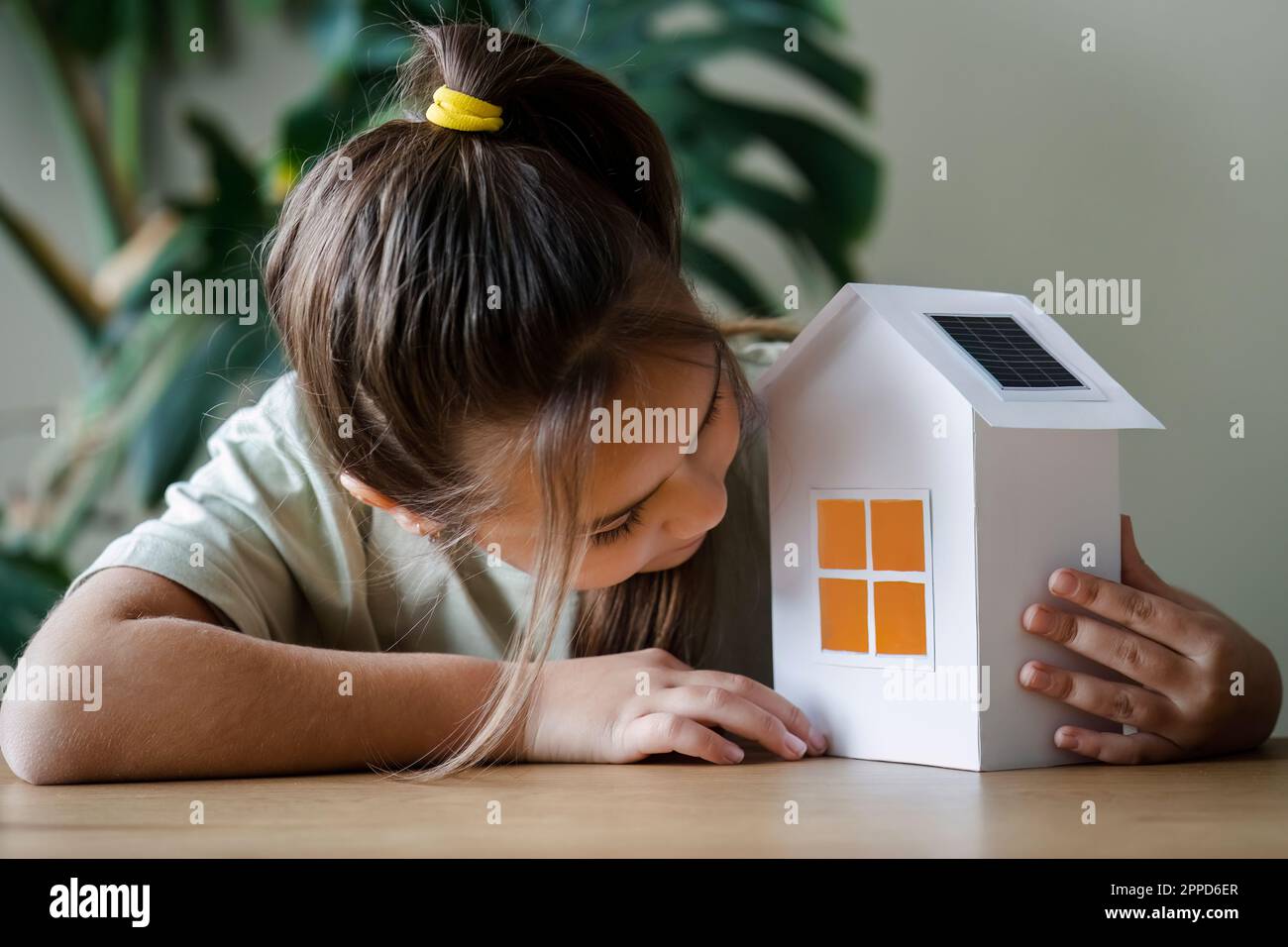 Curious girl looking inside house model on table Stock Photo