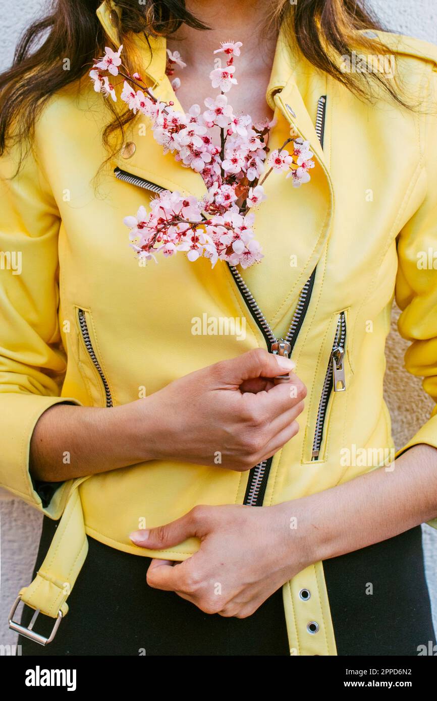 Woman with cherry blossom flowers tucked inside yellow jacket Stock Photo