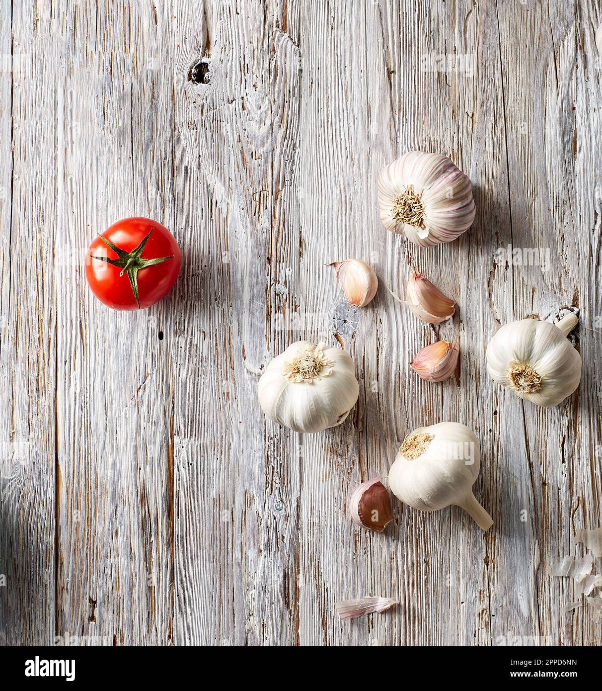 Garlic cloves and single tomato lying on wooden surface Stock Photo - Alamy