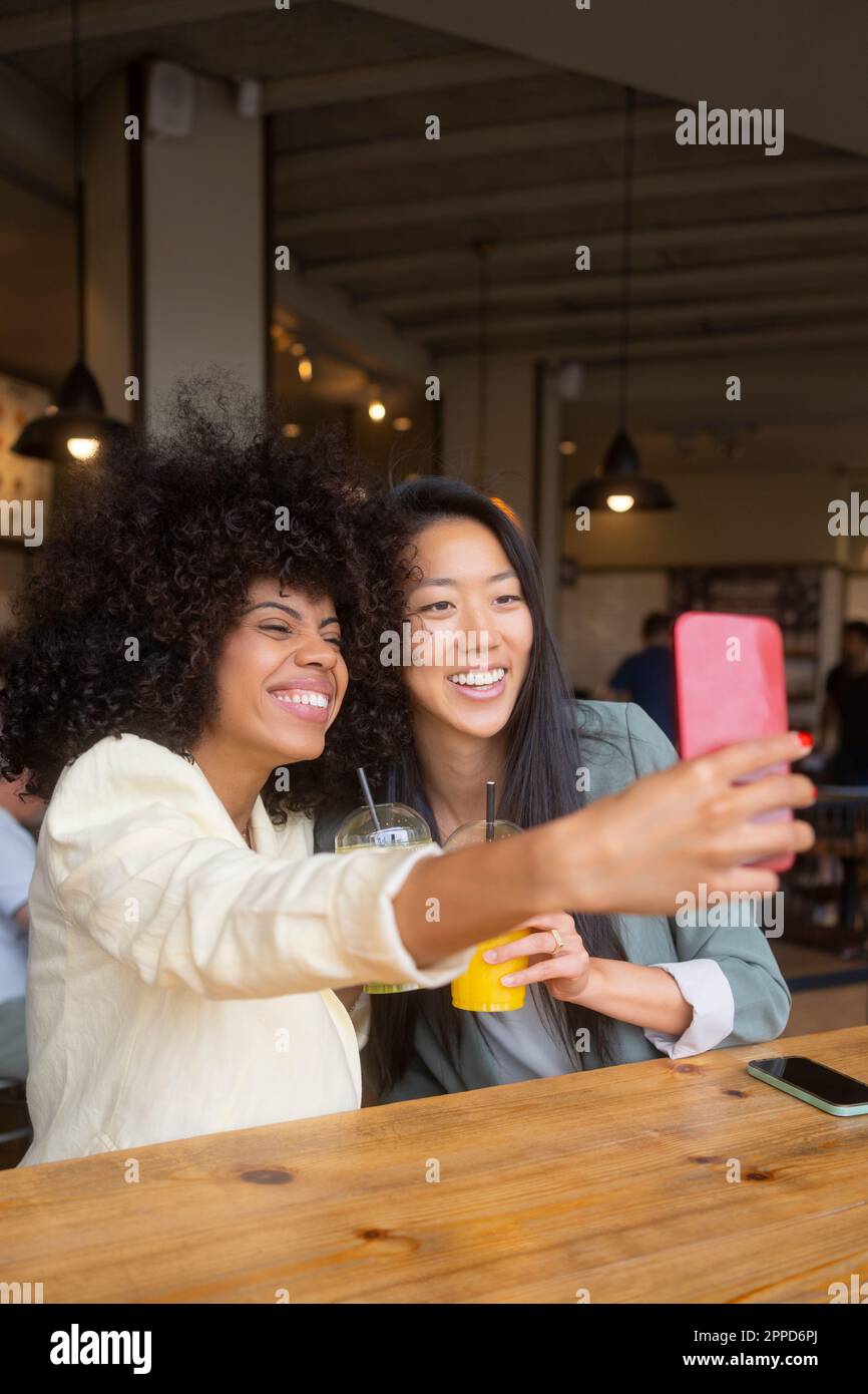 Happy woman taking selfie with friend at cafe Stock Photo - Alamy
