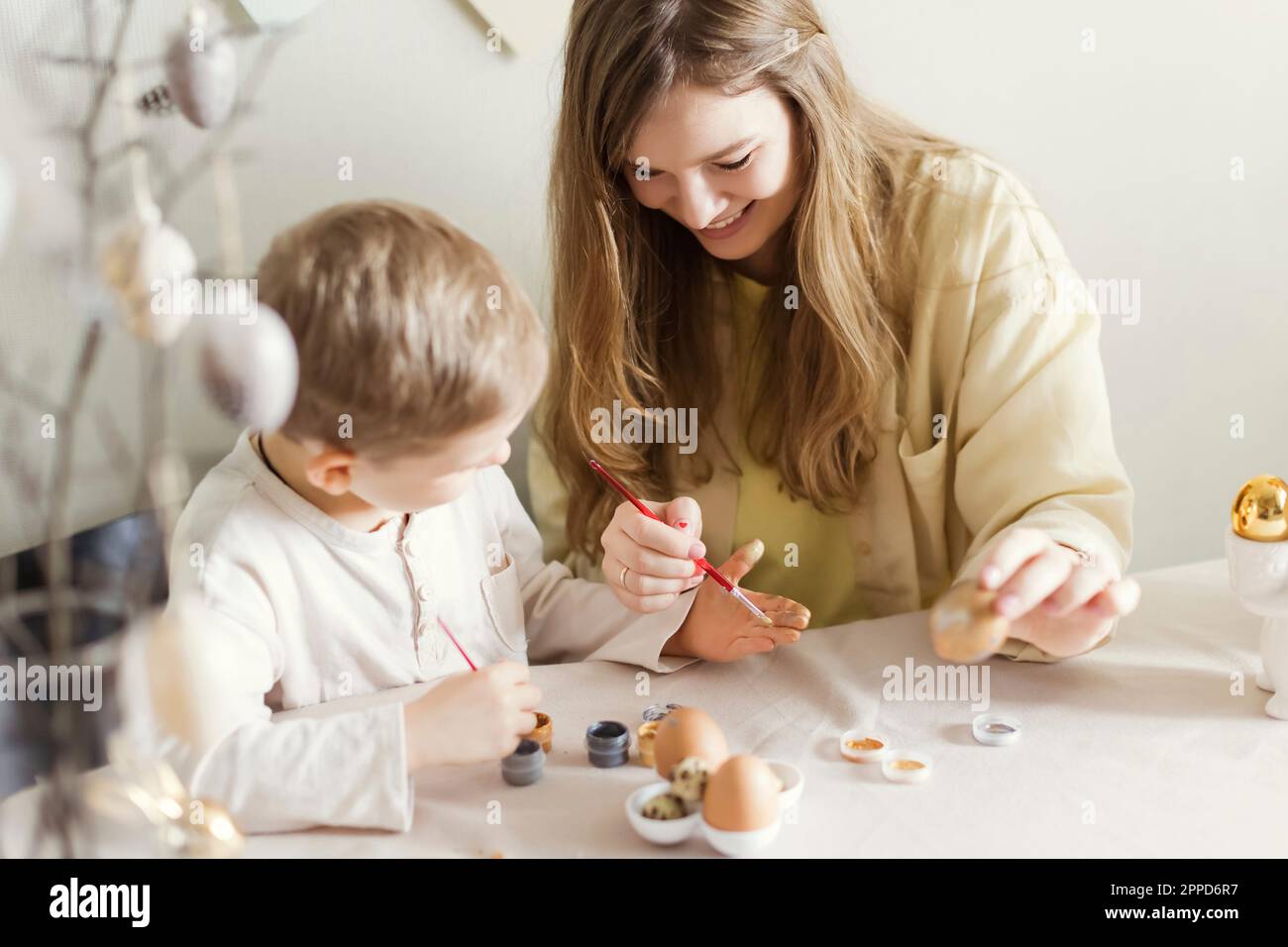 Happy mother and son decorating Easter eggs at home Stock Photo