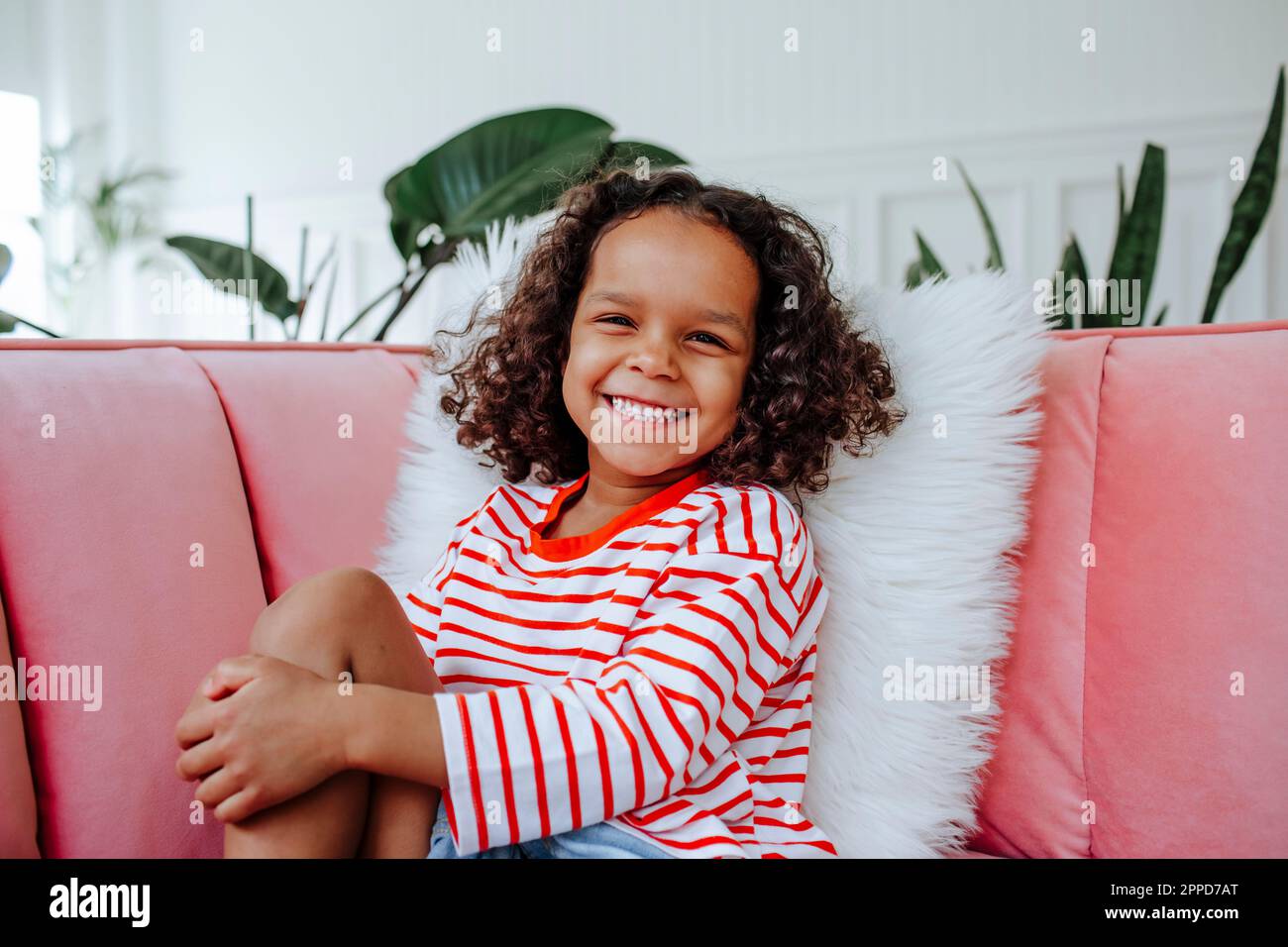 Happy cute girl sitting on sofa at home Stock Photo - Alamy