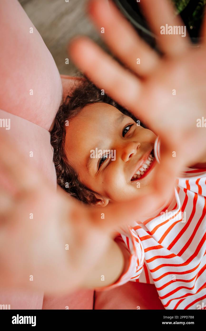 Smiling girl showing stop gesturing on sofa at home Stock Photo