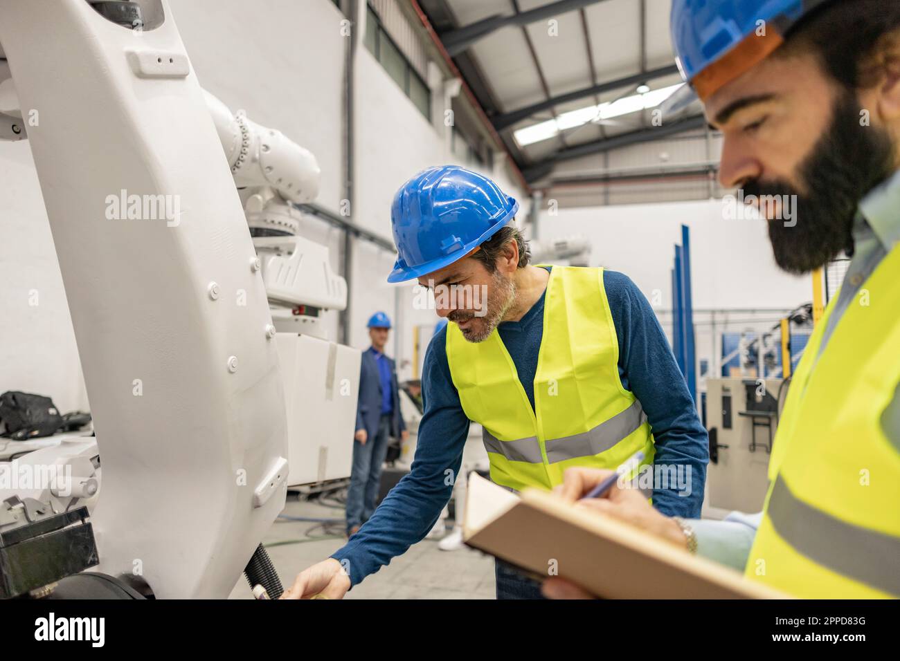 Engineers working on robotic arm in industry Stock Photo