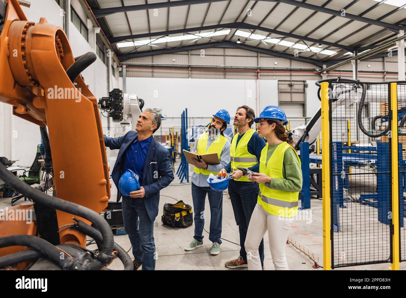 Engineer with colleagues having discussion over robotic arm Stock Photo