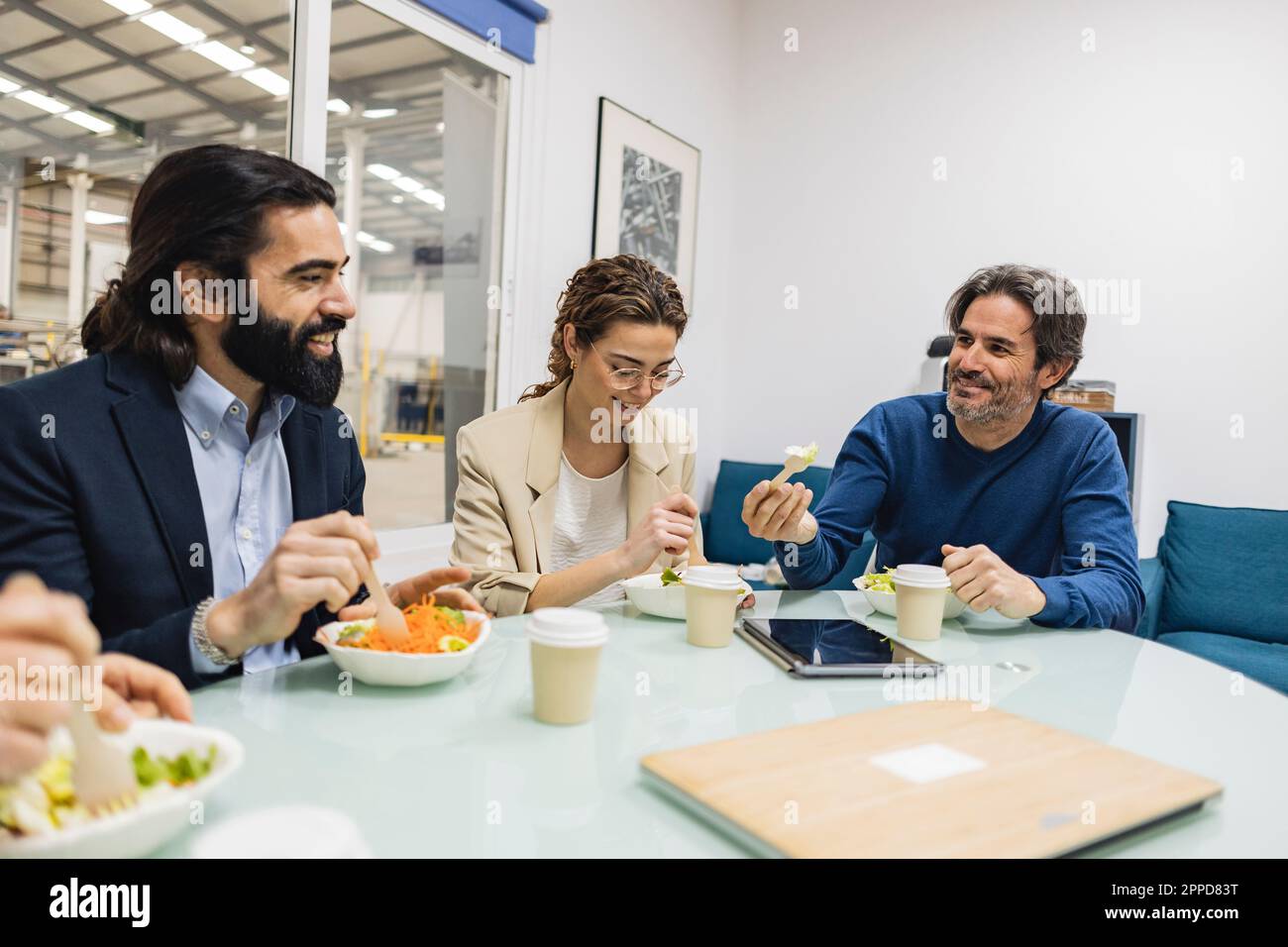 Happy colleagues having meal together in industry Stock Photo