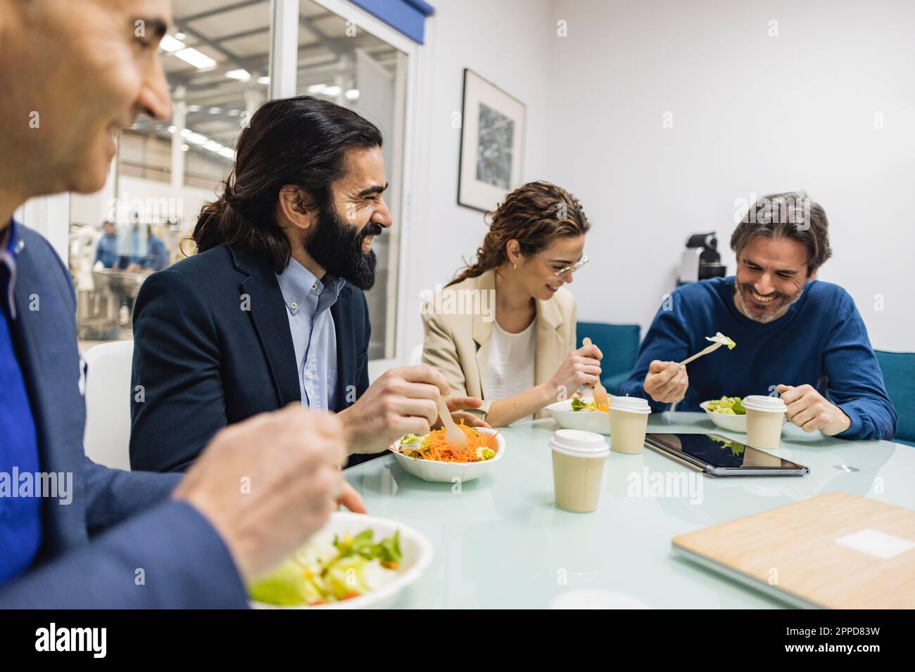 Happy colleagues having meal together at desk Stock Photo