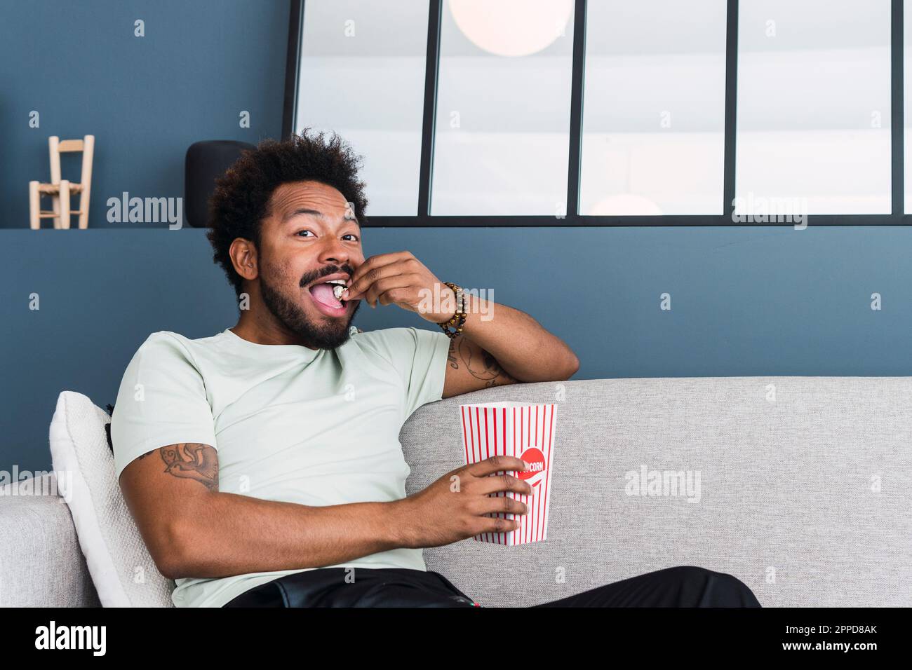 Man eating popcorn sitting on sofa at home Stock Photo Alamy