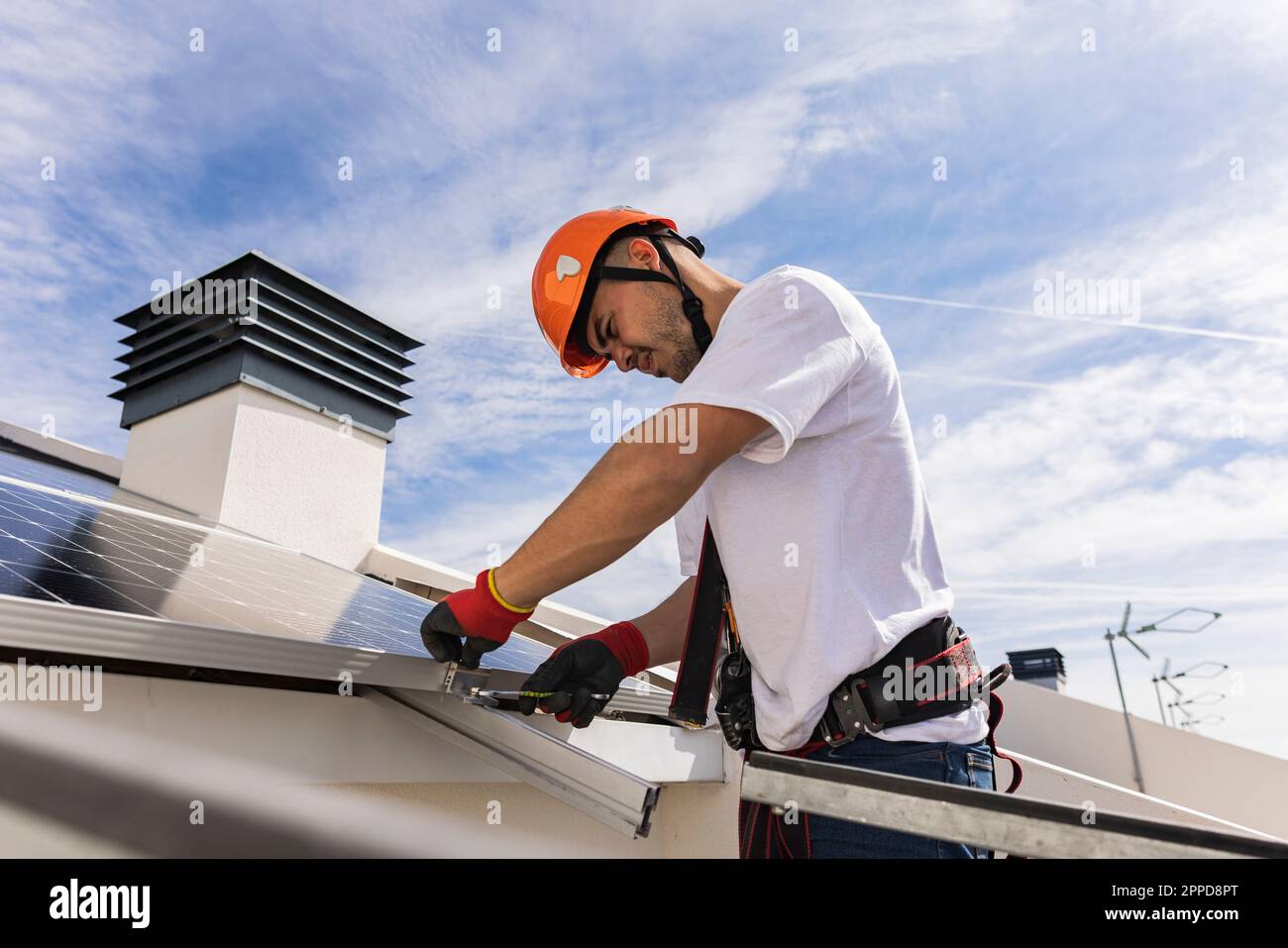 Young engineer wearing hardhat installing solar panels Stock Photo