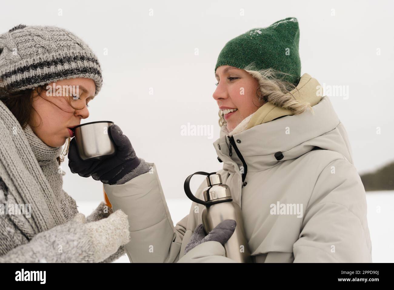 https://c8.alamy.com/comp/2PPD90J/happy-woman-feeding-hot-drink-to-friend-in-winter-2PPD90J.jpg