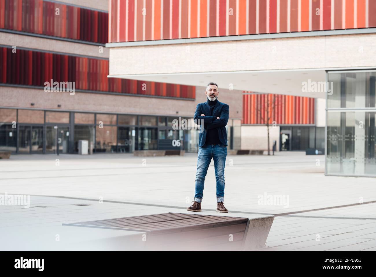Businessman standing with arms crossed in front of building Stock Photo ...
