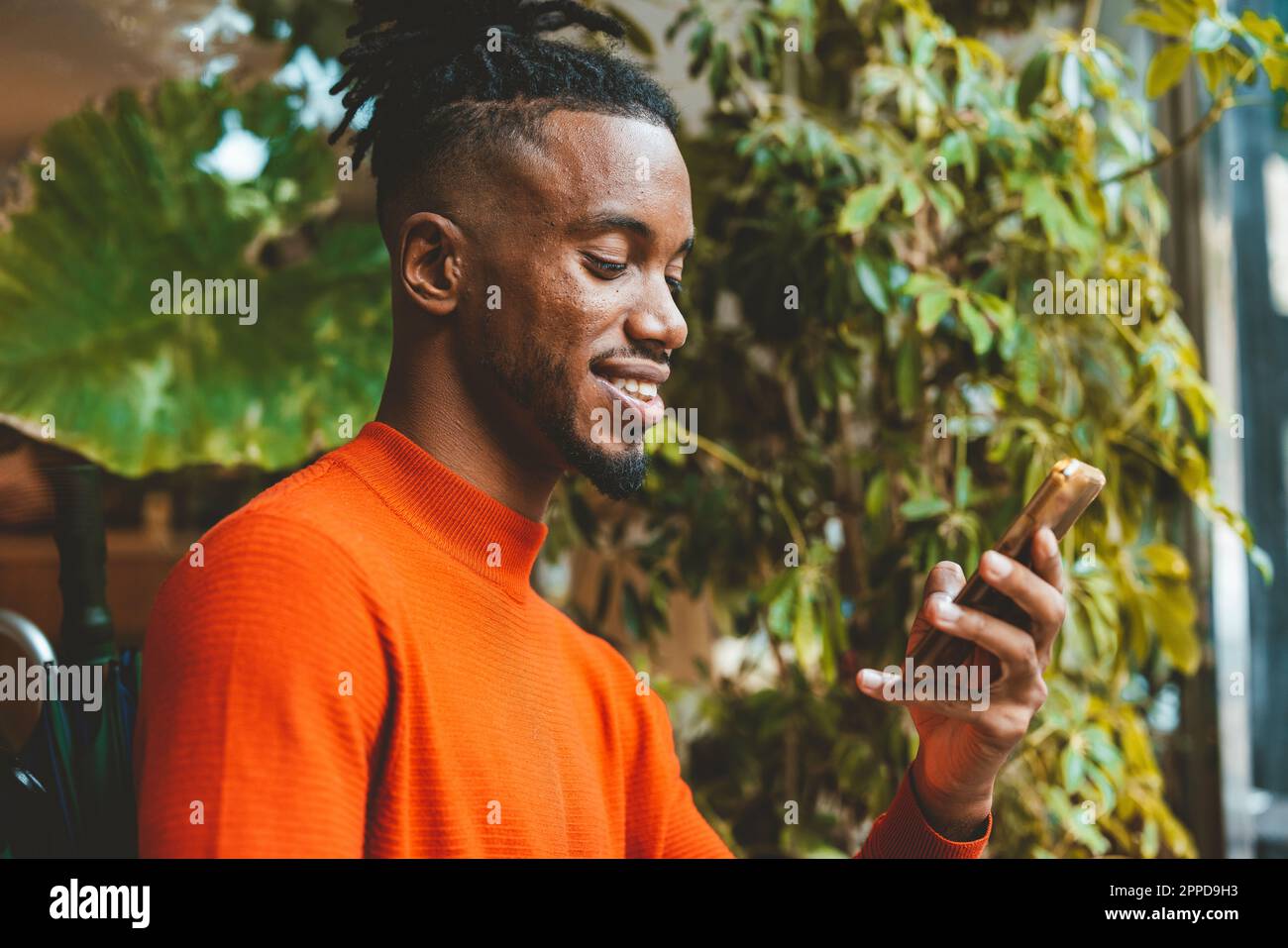 Smiling young man using smart phone Stock Photo