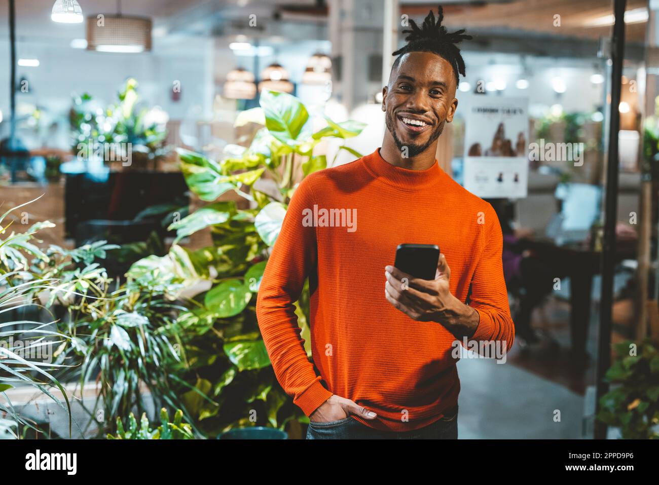Happy young businessman holding mobile phone in office Stock Photo