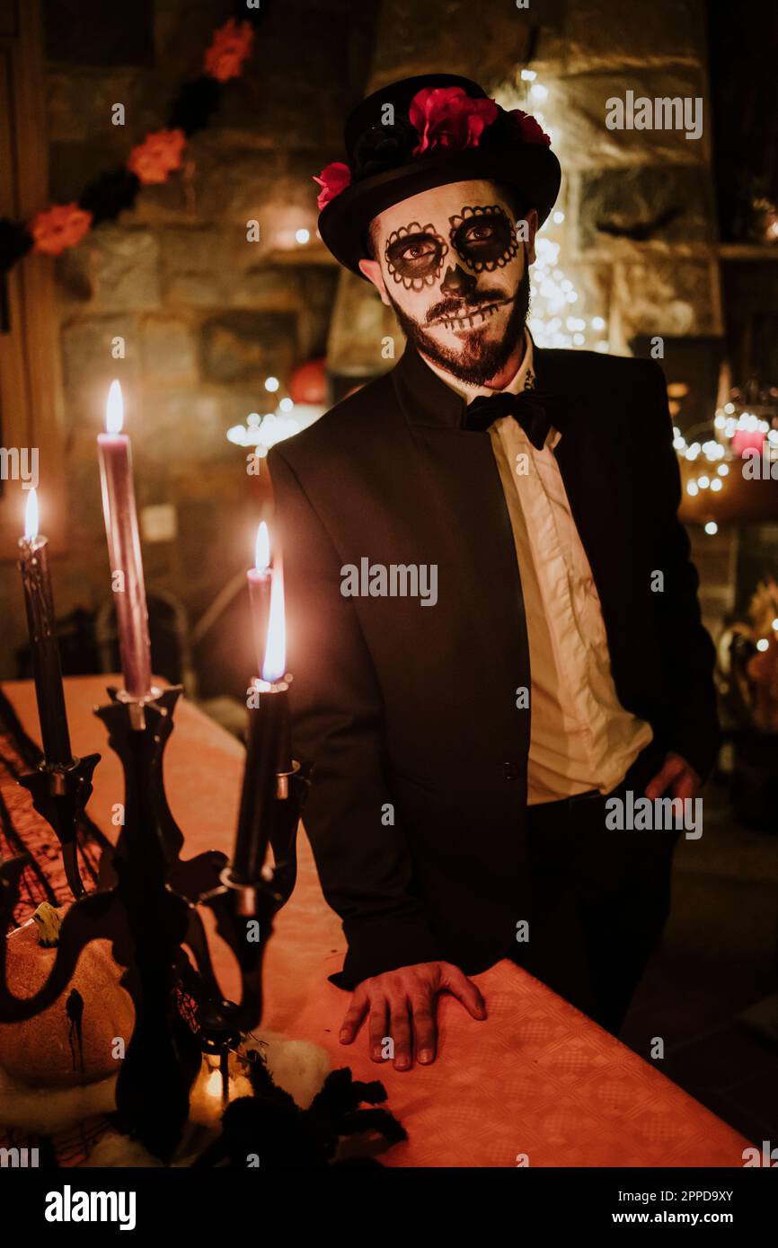 Man wearing Day of the Dead costume standing by table Stock Photo