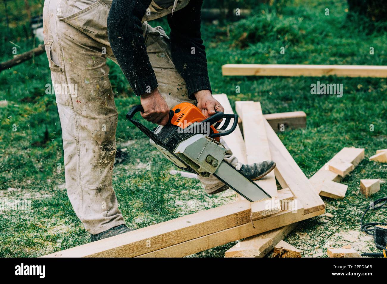 Carpenter cutting wood with chainsaw on grass Stock Photo Alamy