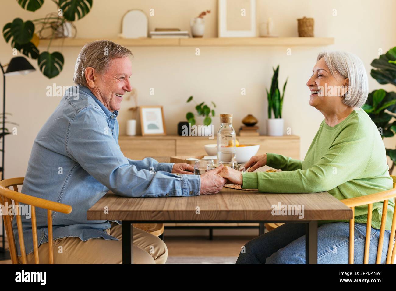 Affectionate senior couple holding hands sitting at dining table Stock Photo