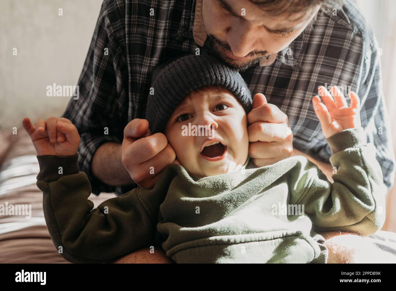 Father wearing knit hat to son at home Stock Photo