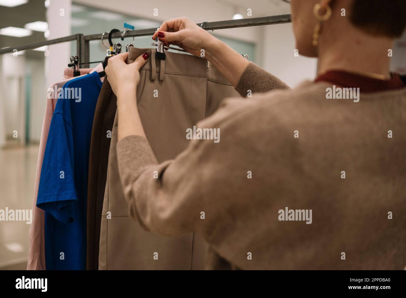 Store owner hanging clothes on rack in store Stock Photo - Alamy
